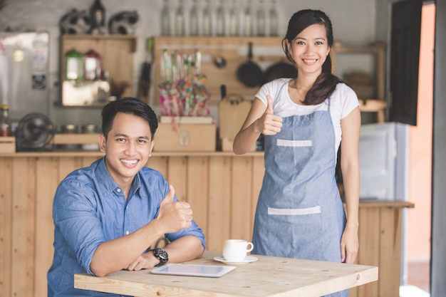 Cliente e garçom feminino aparecendo polegar