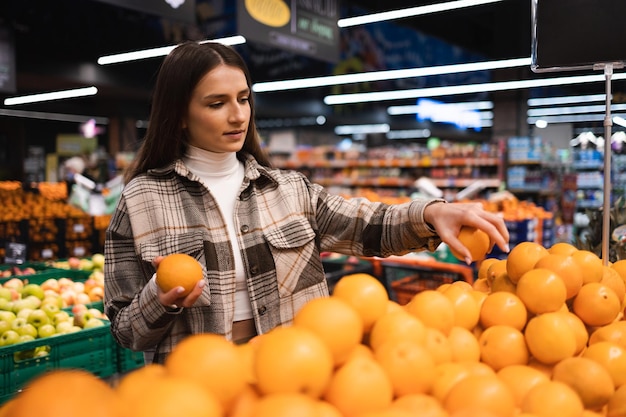 Cliente eligiendo naranjas frescas en el supermercado