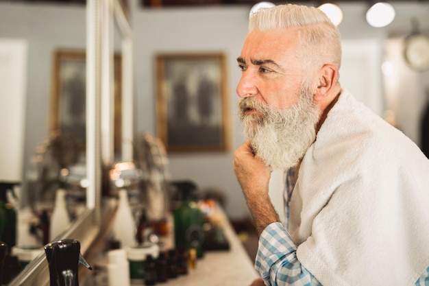 Foto cliente envelhecido, avaliando o trabalho de cabeleireiro na barbearia