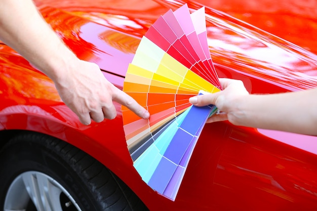 Foto cliente escolhendo cor sobre o fundo vermelho do carro