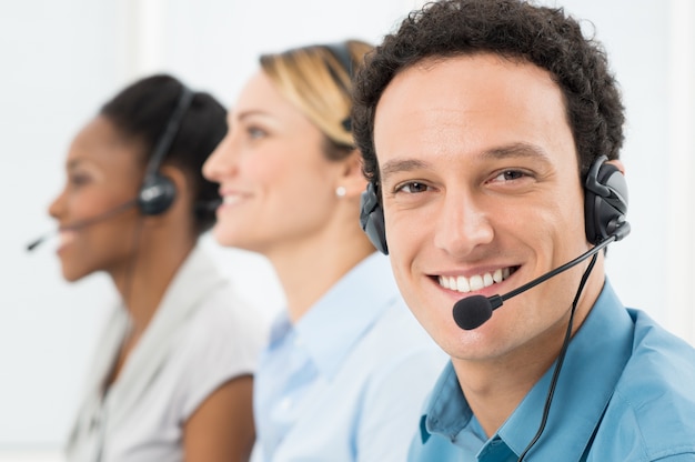 Cliente feliz con auriculares trabajando con otro colega en el centro de llamadas