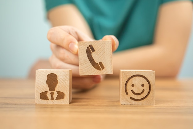 Cliente feliz com fundo de conceito de serviço de call center Ajude o atendimento ao cliente e suporte Cubos de madeira com ícones e mão de jovem no escritório foto