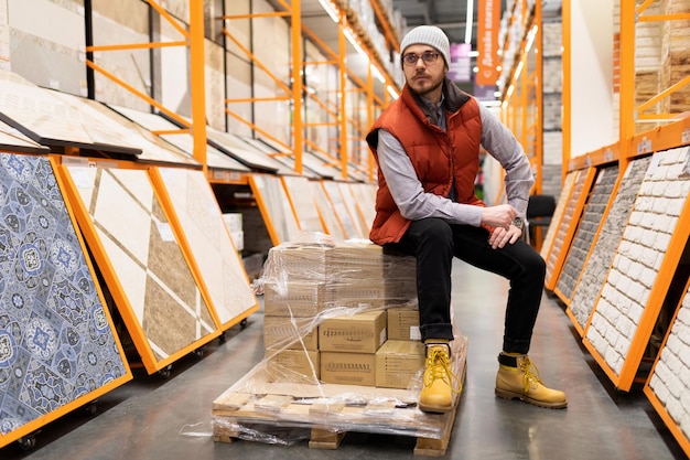 Un cliente en una ferretería se sienta en una caja de baldosas de cerámica.