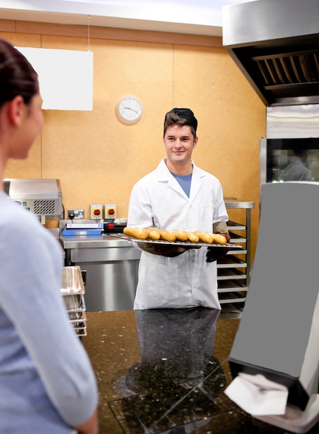 Foto cliente hermoso que espera el pan en una cafetería y que sonríe en el panadero