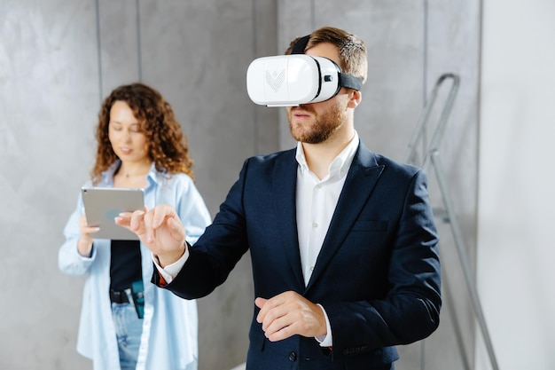 Cliente homem usando óculos VR imaginando o futuro interior em pé com o designer no canteiro de obras O conceito de reparo em um design moderno