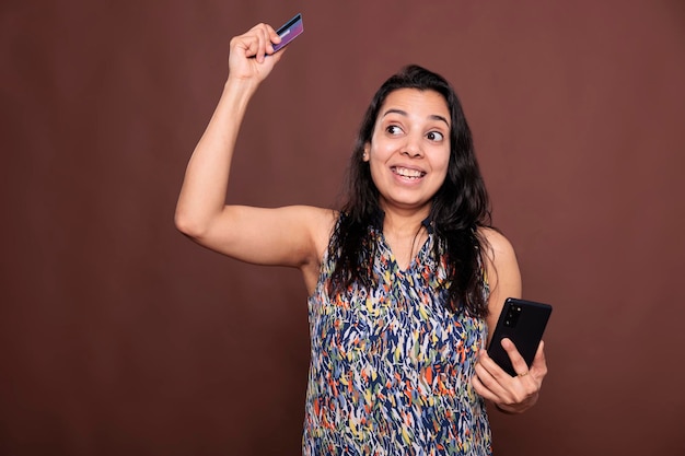 Cliente indio satisfecho haciendo un pedido en la aplicación de teléfono inteligente de la tienda en línea, pago exitoso, mujer india feliz usando el sitio web de comercio electrónico. Cliente que compra productos en una tienda de internet, adicto a las compras