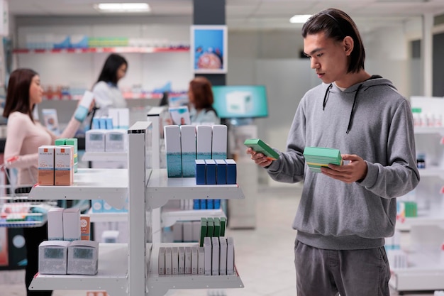 Cliente jovem lendo folheto de caixas de remédios, querendo comprar suprimentos farmacêuticos e tratamento de prescrição. Olhando para pacotes de medicamentos e suplementos para curar doenças de saúde.