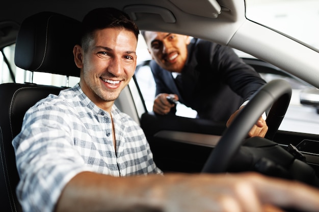 Cliente joven alegre compra un coche nuevo en un concesionario