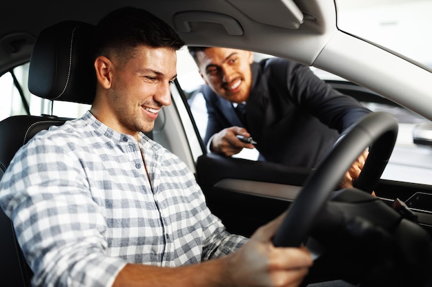 Cliente joven alegre compra un coche nuevo en un concesionario