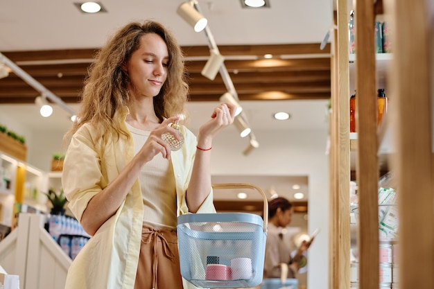 Cliente joven que elige perfume durante sus compras en la tienda de cosméticos