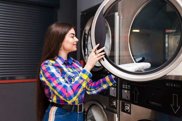 Foto el cliente de lavandería de autoservicio saca las cosas de la secadora