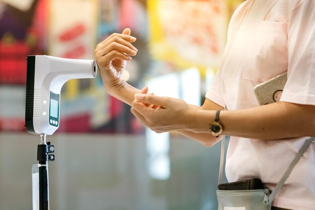 Foto cliente levantó la mano en el termómetro digital con máquina de escaneo de temperatura para la fiebre