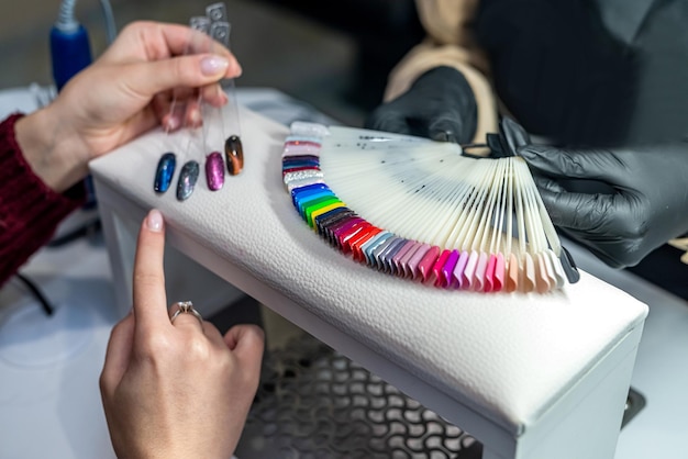 Cliente con maestro eligiendo esmalte de uñas de color en gabinete de manicura y pedicura Nail art