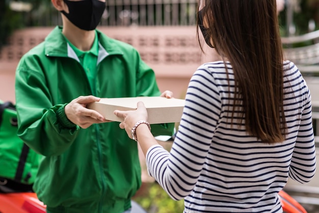 Foto una cliente con máscara facial toma el pedido de pizza del mensajero