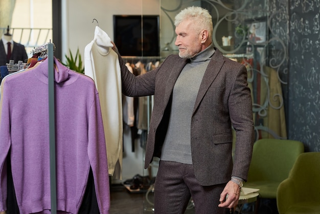 Un cliente masculino con barba viste un traje en una boutique.