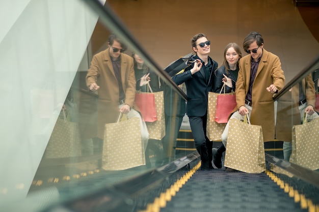 Cliente masculino e feminino na escada rolante no shopping