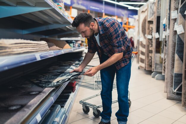 Cliente masculino en una ferretería elige una alfombra para la casa