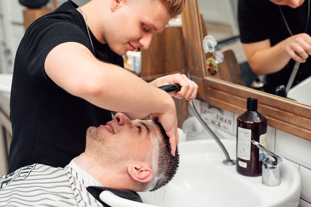 Un cliente masculino se lava el cabello en una barbería