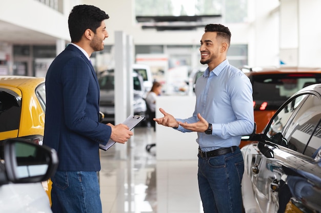 Cliente masculino que elige un coche nuevo en el salón de la concesionaria de automóviles