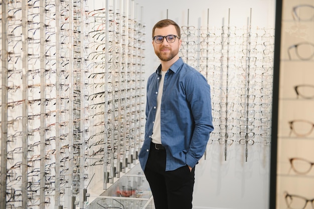 Cliente masculino que elige un nuevo marco de anteojos para sus nuevos anteojos en una tienda óptica