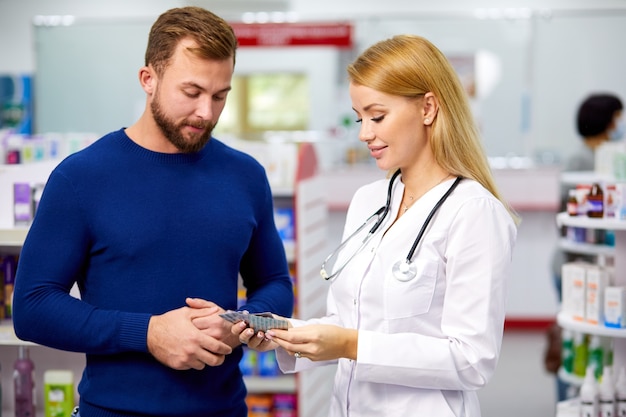 Cliente masculino tener una charla discreta con boticario en farmacia