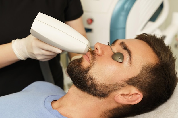 Foto cliente masculino durante el tratamiento ipl en una clínica médica de cosmetología