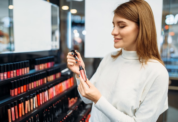 El cliente mira delineador de labios en la tienda de cosméticos