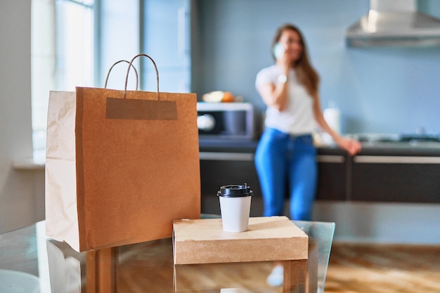 Cliente moderno ocupado casual adulto jovem feliz recebeu sacos de papelão com comida e bebidas para viagem em casa. conceito de serviço de entrega rápida