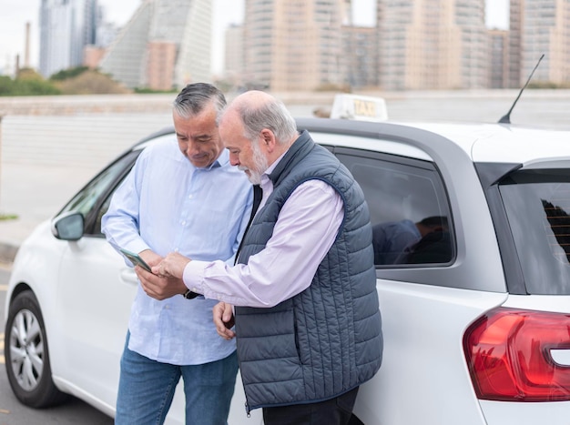 El cliente le muestra al anciano taxista la dirección en el móvil donde quiere ir. Concepto de transporte taxi y tecnología.