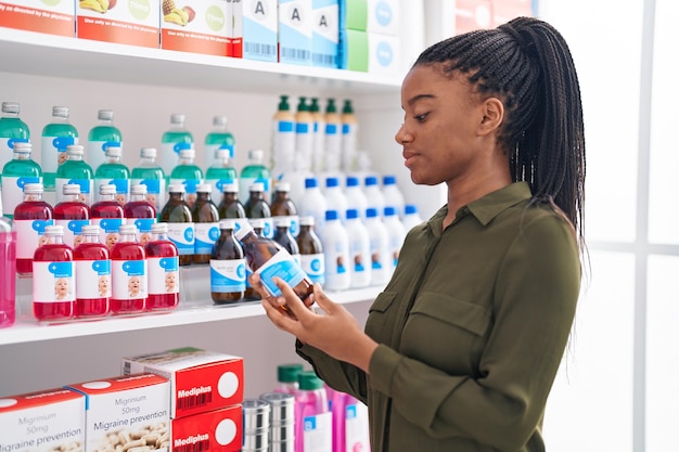 Cliente mujer afroamericana con botella de medicina en la farmacia