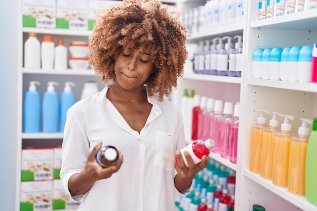 Cliente mujer afroamericana sosteniendo botellas de medicamentos en la farmacia