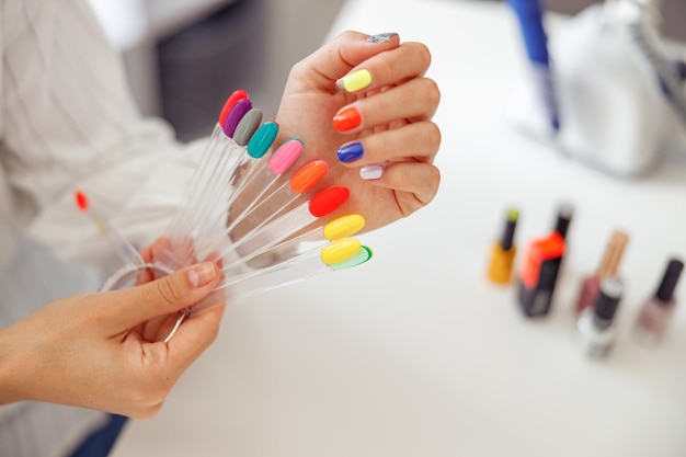 Cliente mujer con paleta de esmaltes de uñas en salón de belleza