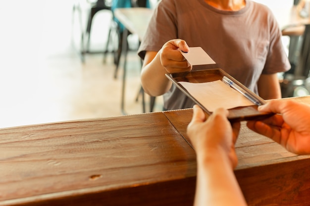 Cliente de las mujeres que da la tarjeta de crédito para que el camarero pague en la cafetería.