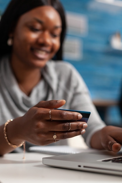 Cliente mulher negra com cartão de crédito, realizando transferência eletrônica e pagando pedidos online