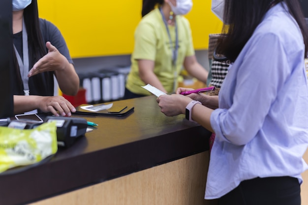 Cliente mulher segurando recibo de transação com cartão de crédito no caixa