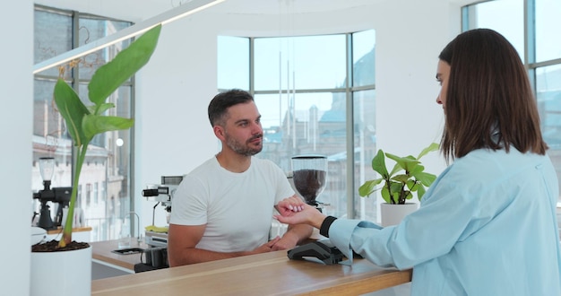 Cliente pagando con un reloj inteligente sin contacto NFC con una máquina de tarjetas Pagando en una cafetería con una tecnología de reloj inteligente