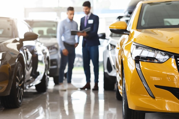 Foto cliente parado entre autos conversando con asistente de ventas