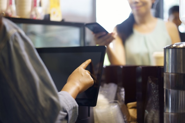 El cliente pide comida y bebida con el uso de su teléfono inteligente y de la alta tecnología de nfs para pagarle a un barista