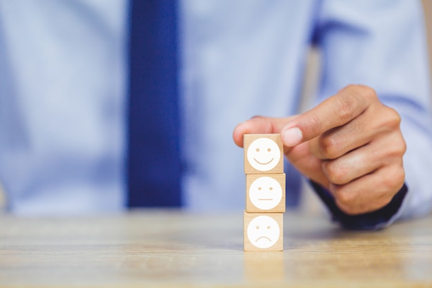 Foto cliente presionando emoticon de cara sonriente en cubo de madera