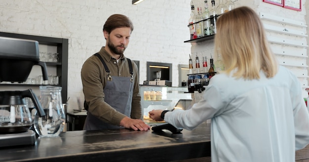 Cliente que paga com um smartwatch sem contato nfc com uma máquina de cartão. pagar em uma cafeteria por um smartwatch. tecnologia.