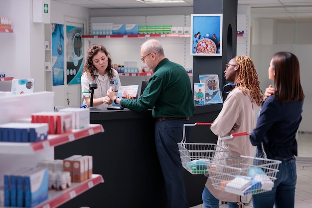 Cliente senior que paga medicamentos de cardiología con reloj moderno usando terminal para pago sin contacto en farmacia. Diversos clientes que compran tratamientos farmacéuticos para maldecir la enfermedad. apoyo a la atención de la salud