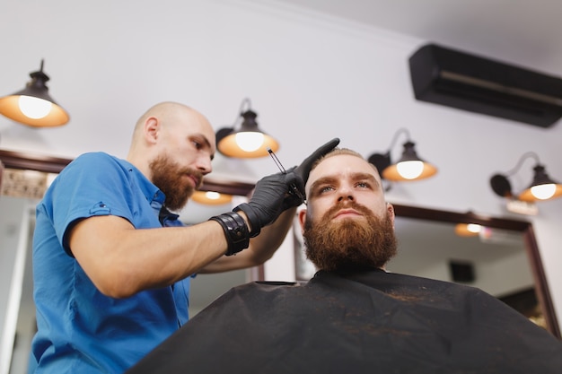 Cliente de servicio de peluquería profesional masculino, afeitado de barba grande y gruesa con navaja de afeitar