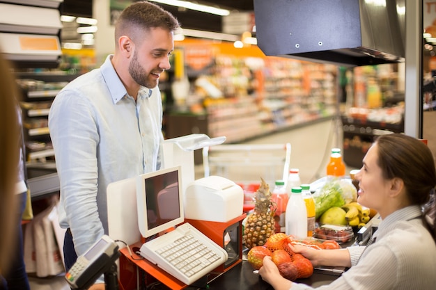 Cliente sonriendo al cajero en supermercado