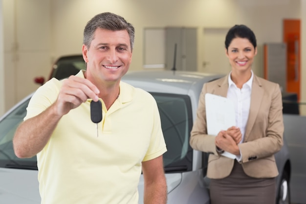 Cliente sonriente que muestra su nueva llave del coche