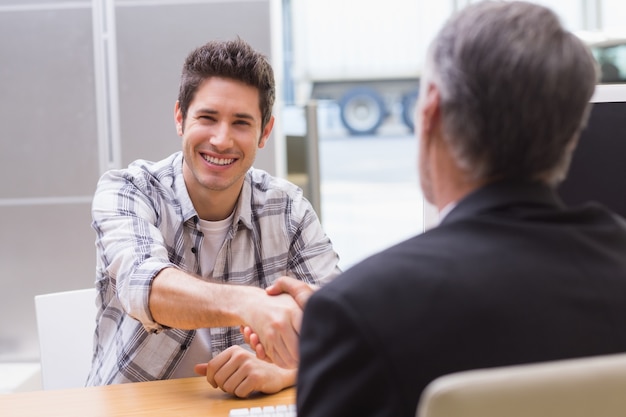 Cliente sorridente sacudindo uma mão de vendedor