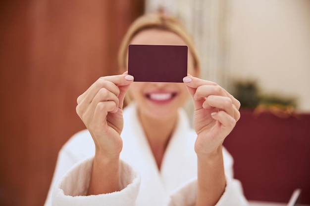 Foto cliente de spa que cubre su rostro con una tarjeta