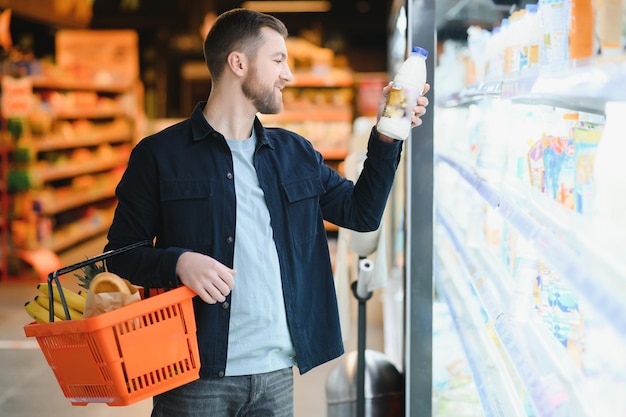 Cliente En El Supermercado Hombre Haciendo Compras De Comestibles De Pie Con El Carro Eligiendo Productos Alimenticios En El Interior Chico Comprando Comestibles En La Tienda De Alimentos Enfoque Selectivo Espacio De Copia