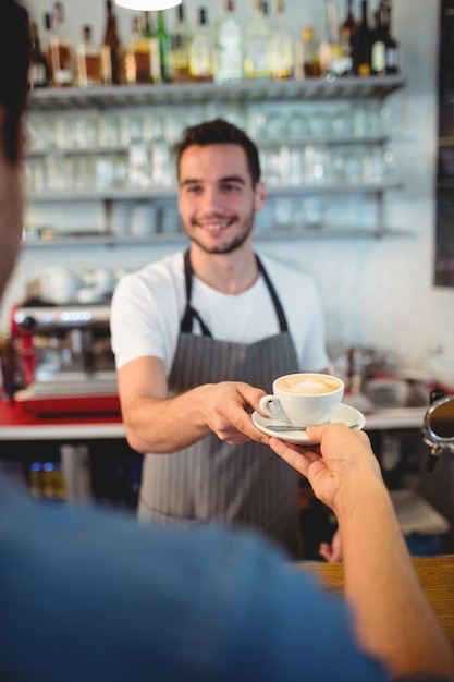 Cliente tomando café de feliz camarero en cafe