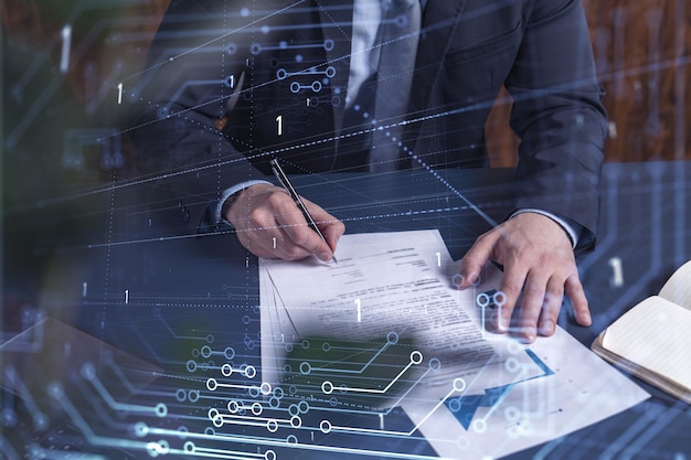 Un cliente con traje azul oscuro está firmando un contrato para crear un nuevo software para presentarlo en una conferencia de inicio y obtener inversiones para crear un producto. Gráfico tecnológico sobre el escritorio.