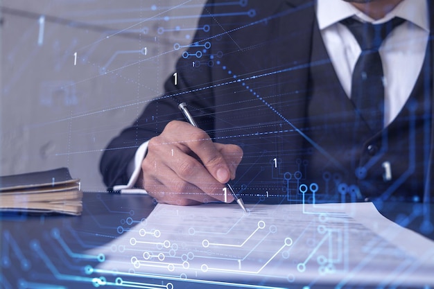 Un cliente con traje azul oscuro está firmando un contrato para crear un nuevo software para presentarlo en una conferencia de inicio y obtener inversiones para crear un producto. Gráfico tecnológico sobre el escritorio.
